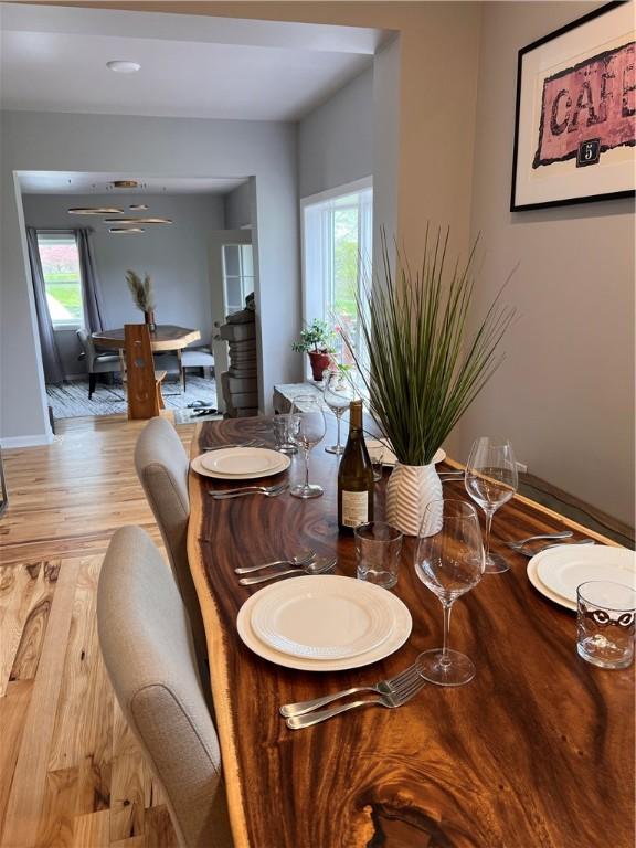 dining area featuring baseboards, light wood finished floors, and a healthy amount of sunlight