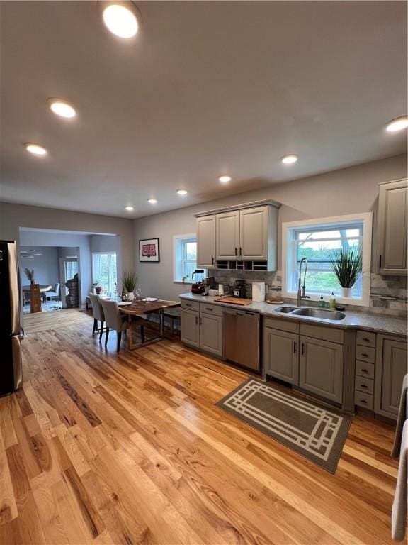 kitchen with a sink, appliances with stainless steel finishes, gray cabinets, and backsplash