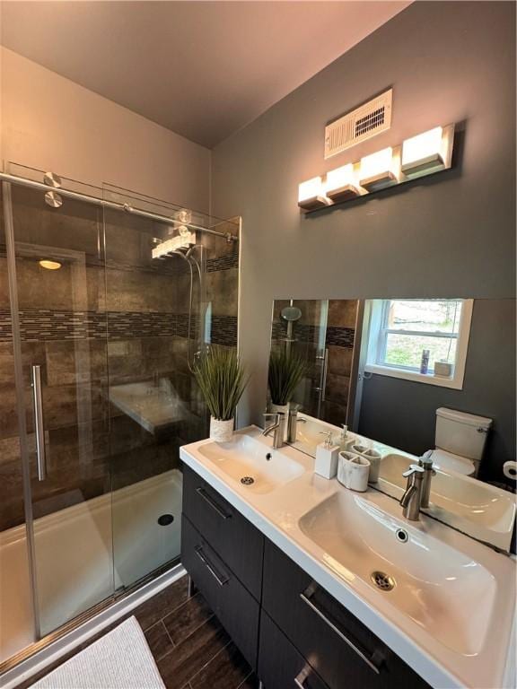 full bath with visible vents, a sink, a stall shower, and toilet