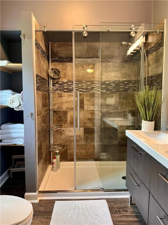 full bathroom with vanity, a stall shower, toilet, and wood finished floors