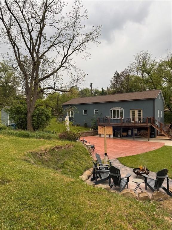 rear view of house with a lawn, a deck, a patio, and an outdoor fire pit