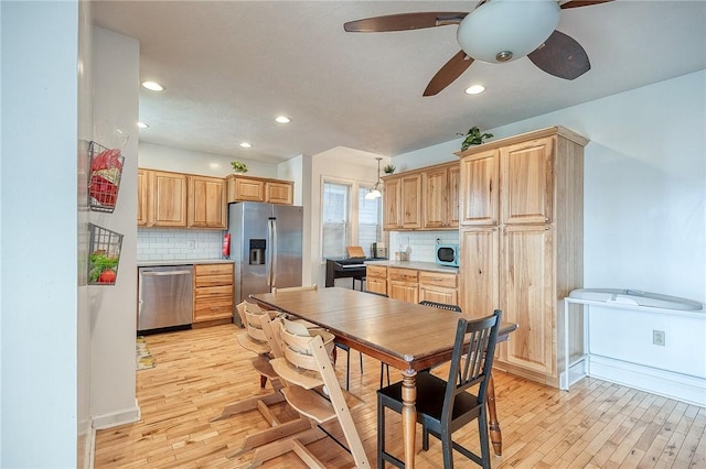 kitchen with light brown cabinetry, stainless steel appliances, decorative backsplash, and light wood-style floors