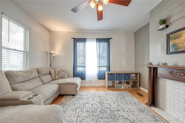 living area featuring a ceiling fan, baseboards, and light wood-style floors