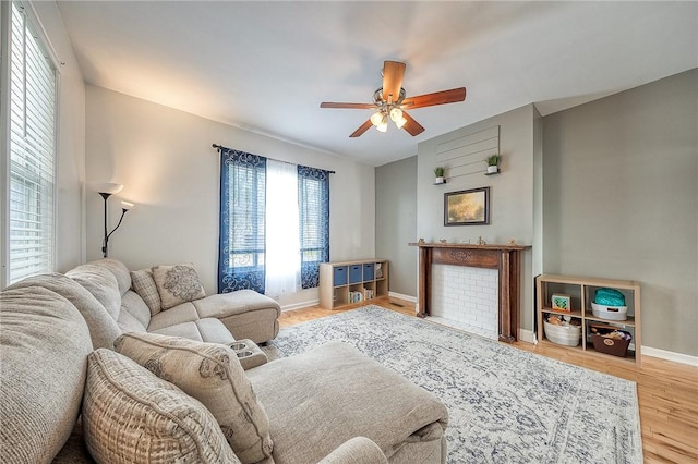 living room featuring baseboards, ceiling fan, and wood finished floors