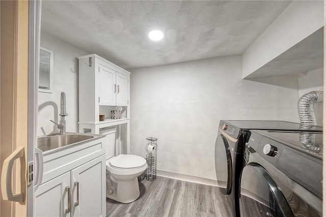 laundry room featuring laundry area, light wood-style floors, baseboards, separate washer and dryer, and a sink