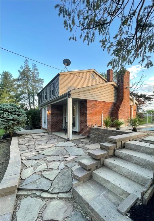 1202 Oakridge Rd, South Fayette, PA 15057 - rear view of property featuring a patio area, brick siding, stairway, and a chimney