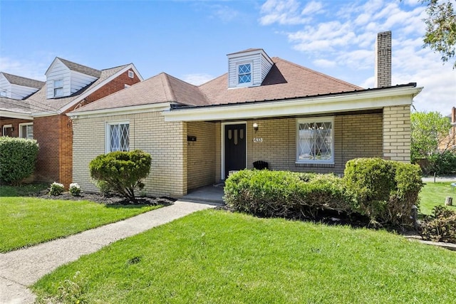 view of front of property featuring brick siding, a chimney, and a front yard