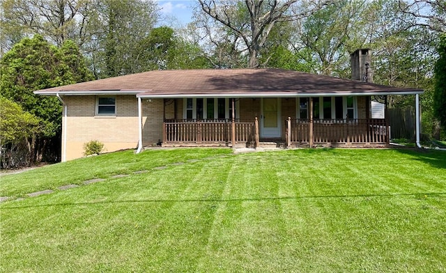 single story home featuring a chimney, a porch, brick siding, and a front yard