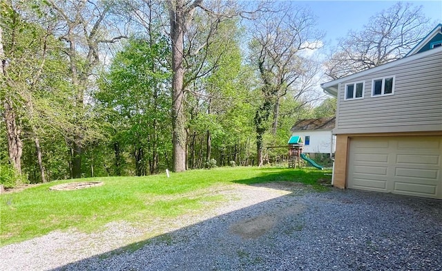 view of yard with a playground, driveway, and a garage