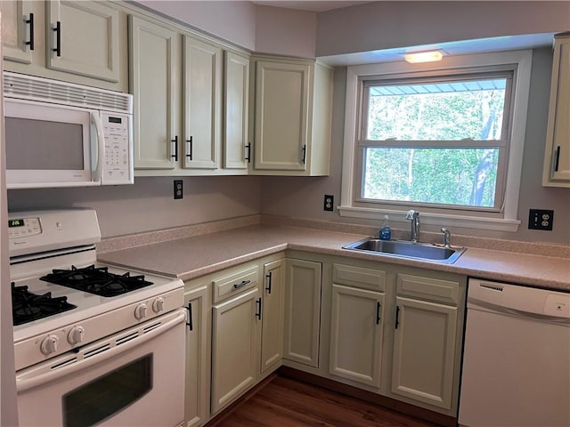 kitchen with white appliances, dark wood-style floors, a sink, and light countertops