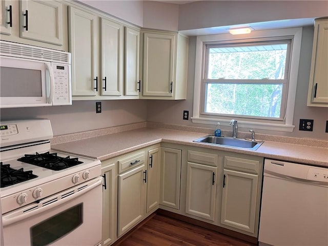 kitchen with white appliances, dark wood-style floors, a sink, and light countertops