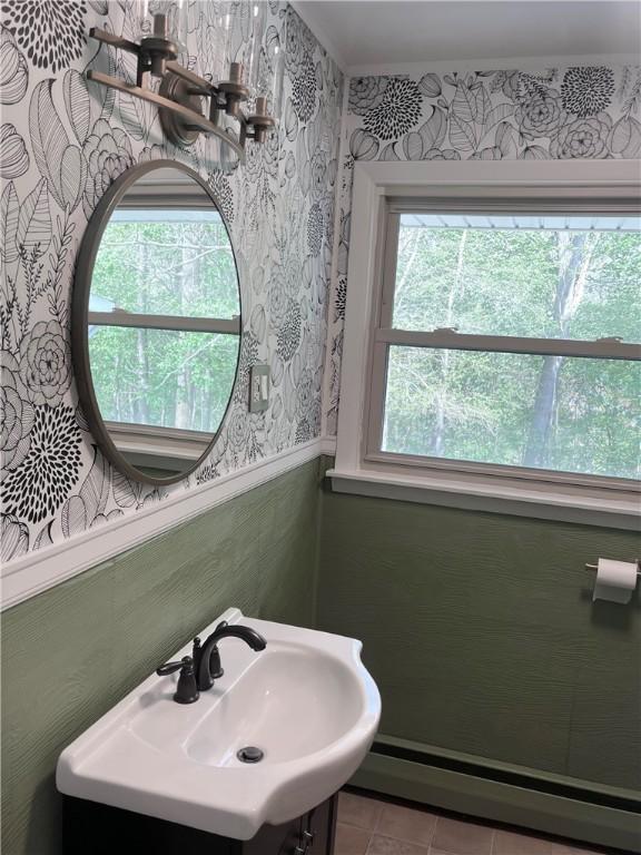 bathroom featuring a sink, wainscoting, wallpapered walls, tile patterned floors, and a baseboard radiator