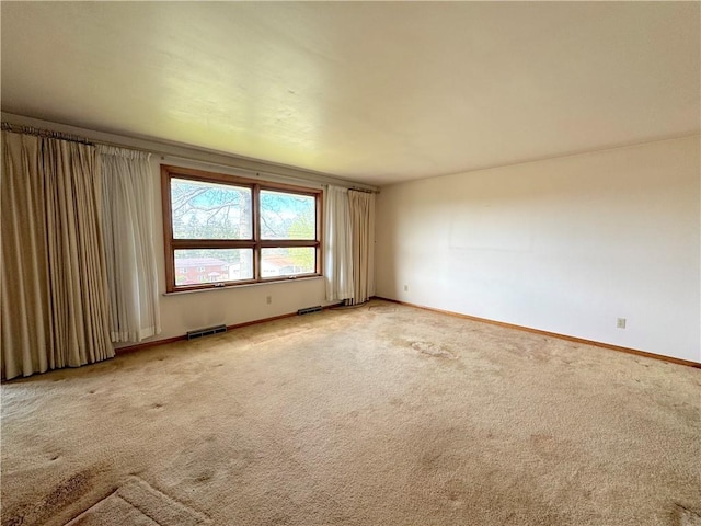 spare room featuring visible vents, baseboards, and light carpet