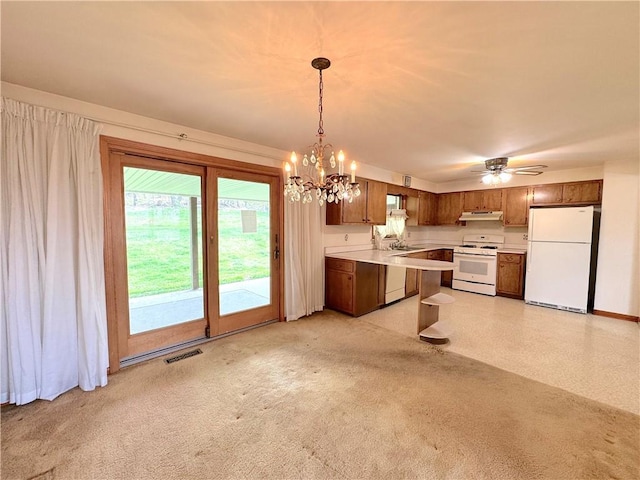 kitchen featuring brown cabinetry, visible vents, light countertops, under cabinet range hood, and white appliances