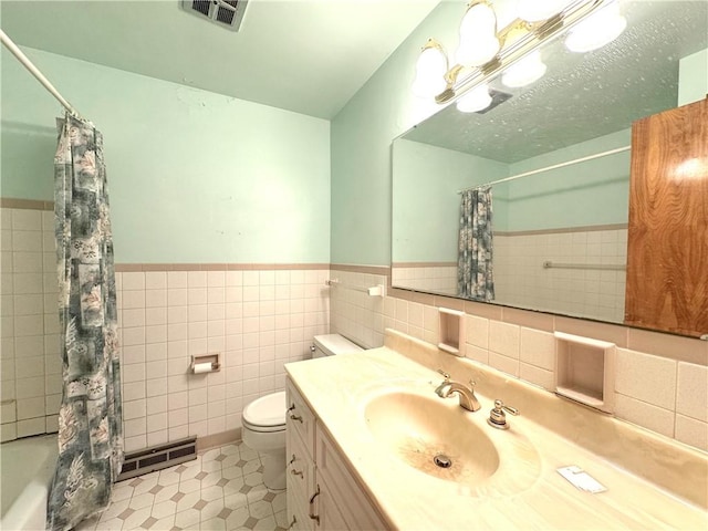 full bathroom featuring tile walls, a wainscoted wall, toilet, and visible vents