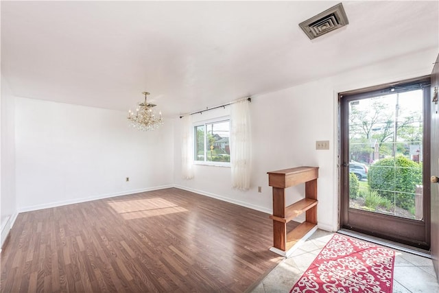 foyer entrance featuring baseboards, visible vents, an inviting chandelier, and wood finished floors