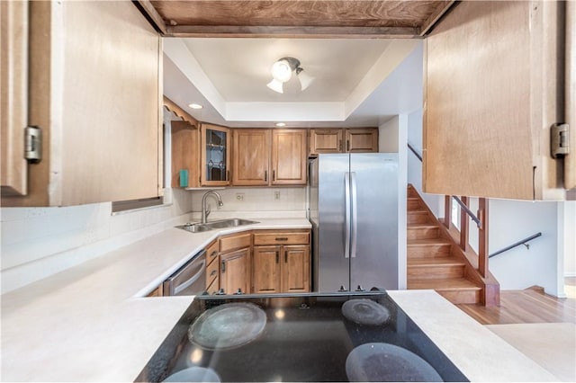 kitchen featuring a sink, appliances with stainless steel finishes, a tray ceiling, and light countertops
