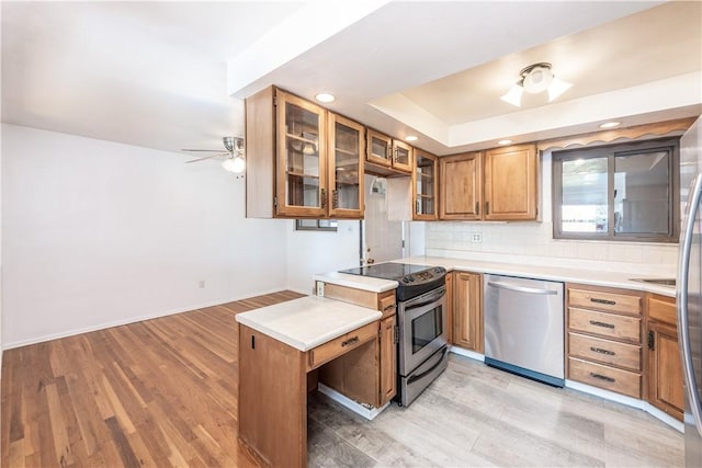 kitchen with light wood-type flooring, light countertops, ceiling fan, and stainless steel appliances