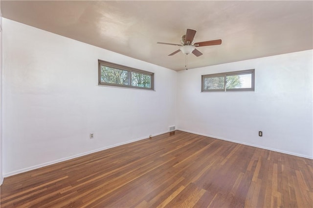 unfurnished room with baseboards, dark wood-style flooring, and a healthy amount of sunlight