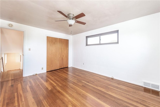 unfurnished bedroom with visible vents, wood-type flooring, baseboards, and a closet