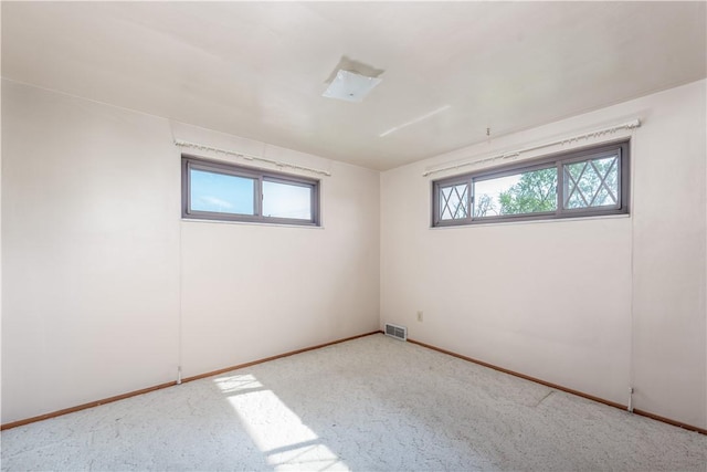 empty room with carpet floors, baseboards, and visible vents