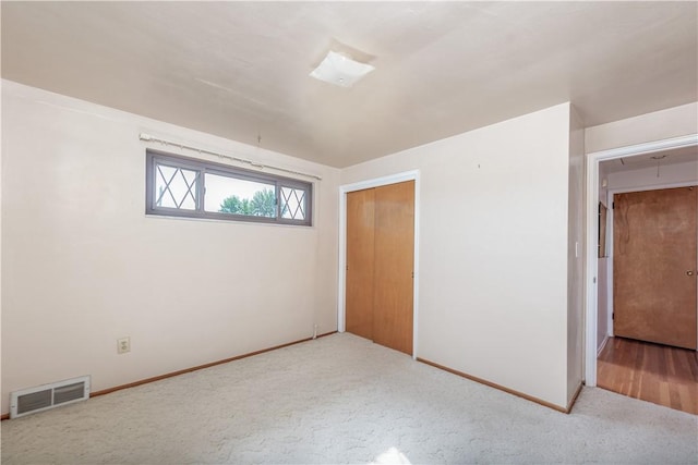 unfurnished bedroom with baseboards, a closet, carpet flooring, and visible vents