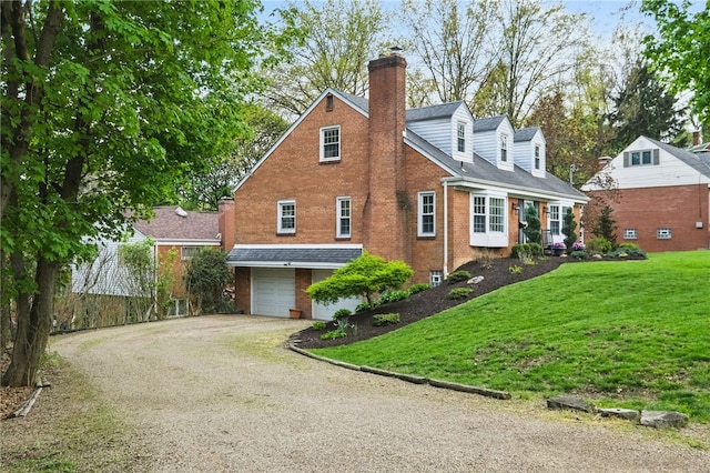 view of property exterior with brick siding, a garage, a chimney, a lawn, and driveway