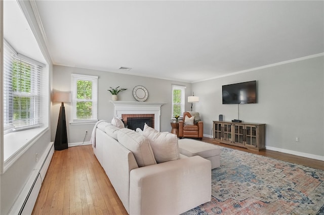 living room with crown molding, light wood-style floors, a fireplace, and a baseboard radiator