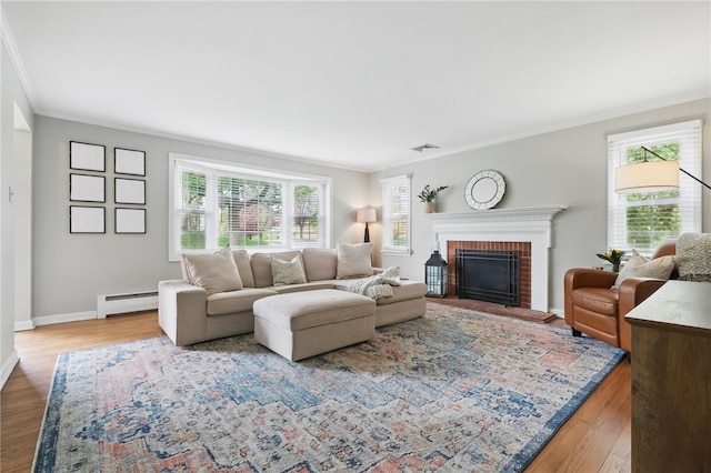 living area featuring crown molding, a wealth of natural light, baseboard heating, and a fireplace