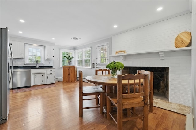 dining area with visible vents, a brick fireplace, recessed lighting, a baseboard heating unit, and light wood-style flooring
