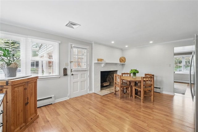 dining area featuring visible vents, a brick fireplace, baseboard heating, a baseboard radiator, and light wood-style flooring