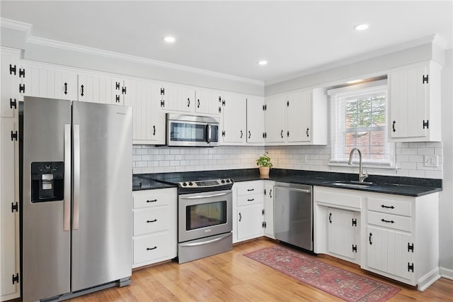 kitchen with stainless steel appliances, dark countertops, white cabinetry, and a sink