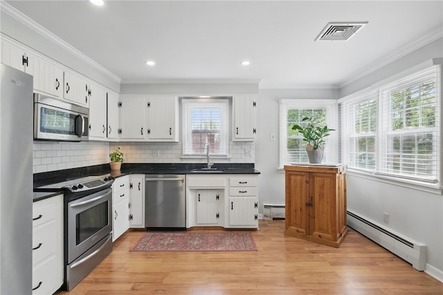 kitchen featuring a sink, a baseboard heating unit, dark countertops, and stainless steel appliances