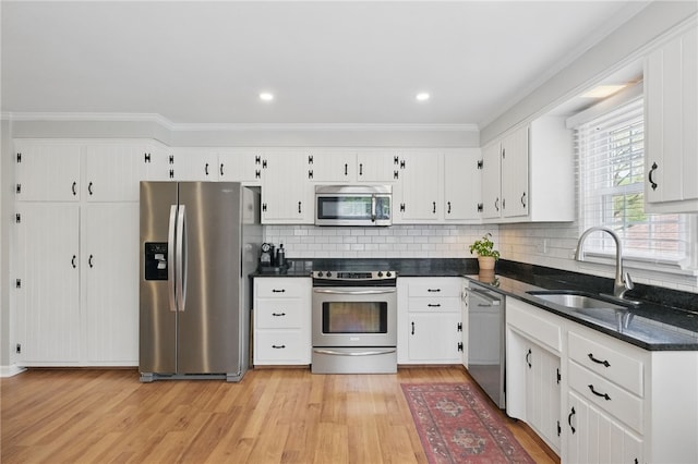 kitchen featuring backsplash, a sink, light wood-style floors, stainless steel appliances, and white cabinetry