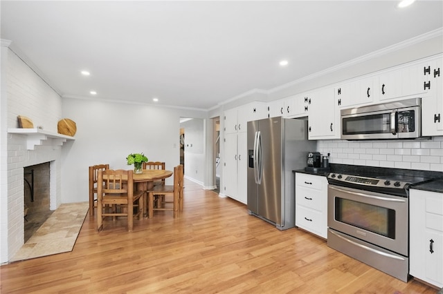 kitchen featuring dark countertops, appliances with stainless steel finishes, ornamental molding, and light wood-type flooring