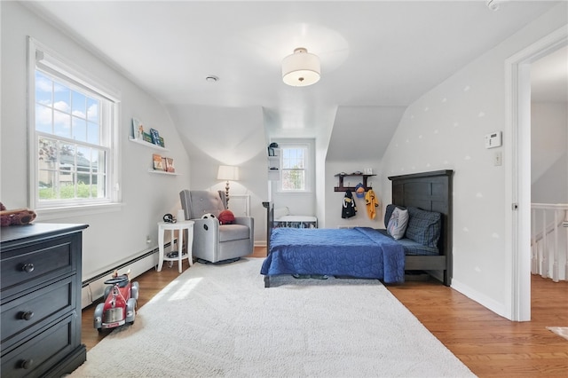 bedroom featuring a baseboard radiator, multiple windows, wood finished floors, and lofted ceiling