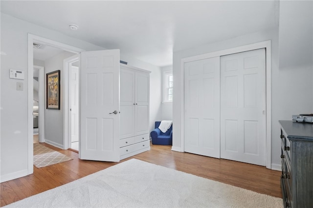 unfurnished bedroom featuring baseboards, wood finished floors, and visible vents