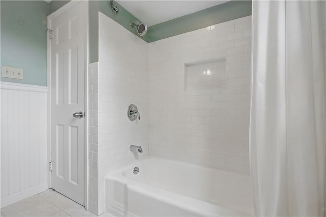 bathroom featuring tile patterned flooring, shower / bathtub combination with curtain, and a wainscoted wall