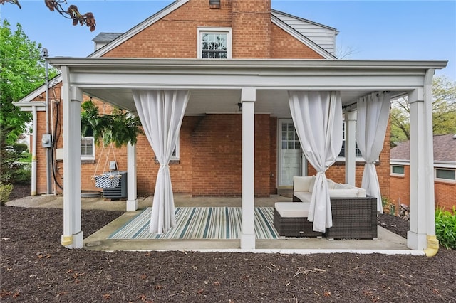 back of house featuring covered porch, brick siding, and a chimney