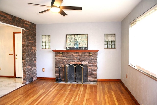 unfurnished living room featuring baseboards, ceiling fan, a fireplace, and wood finished floors