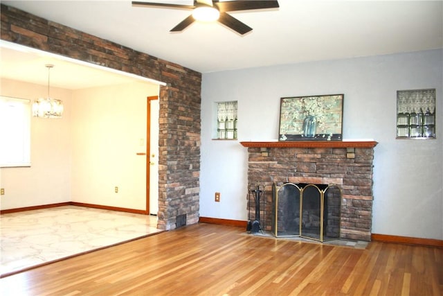 unfurnished living room featuring baseboards, a fireplace with flush hearth, wood finished floors, and ceiling fan with notable chandelier