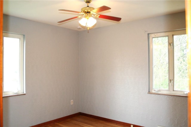 spare room featuring baseboards, ceiling fan, a healthy amount of sunlight, and wood finished floors