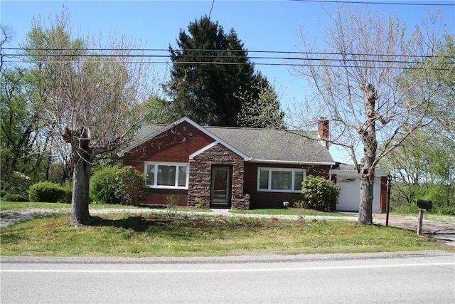 view of front of house with a front lawn, stone siding, a garage, a chimney, and concrete driveway