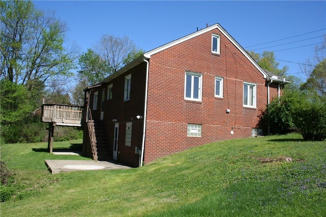 view of home's exterior featuring a lawn, brick siding, and a deck
