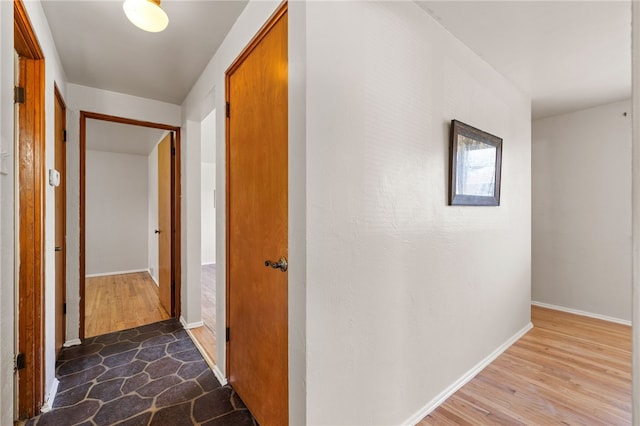 hall with baseboards and wood finished floors