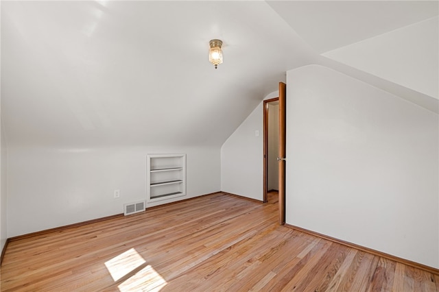 additional living space with built in features, visible vents, wood finished floors, and lofted ceiling