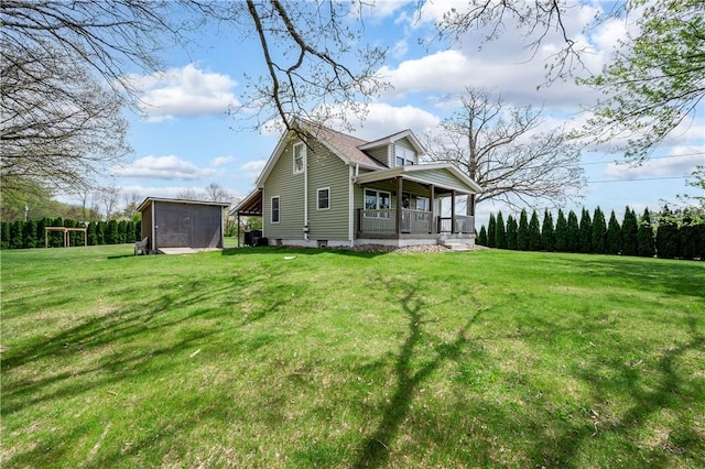 rear view of property featuring a porch, an outdoor structure, a lawn, and a storage unit