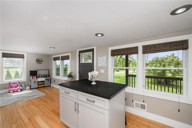 kitchen featuring visible vents, dark countertops, open floor plan, white cabinets, and light wood finished floors