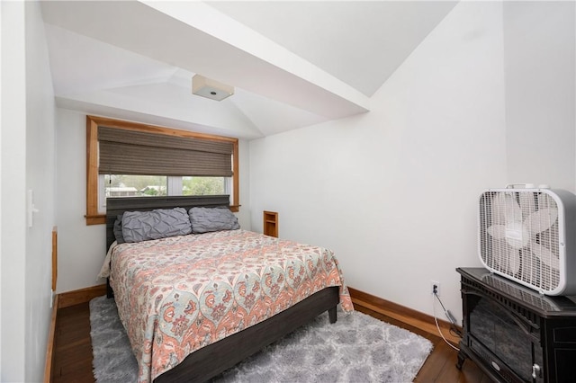 bedroom with baseboards, lofted ceiling, wood finished floors, and a wood stove