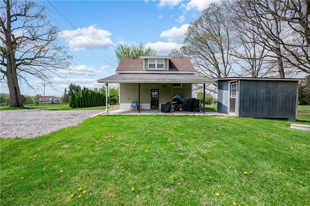 back of property with a lawn, an outdoor structure, and roof with shingles